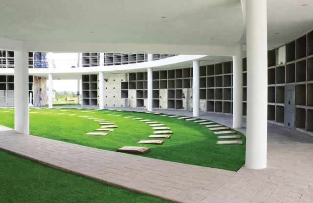 Patio interior del edificio de nichos: césped con placas en semicírculo, columnas blancas y los muros de nichos alrededor